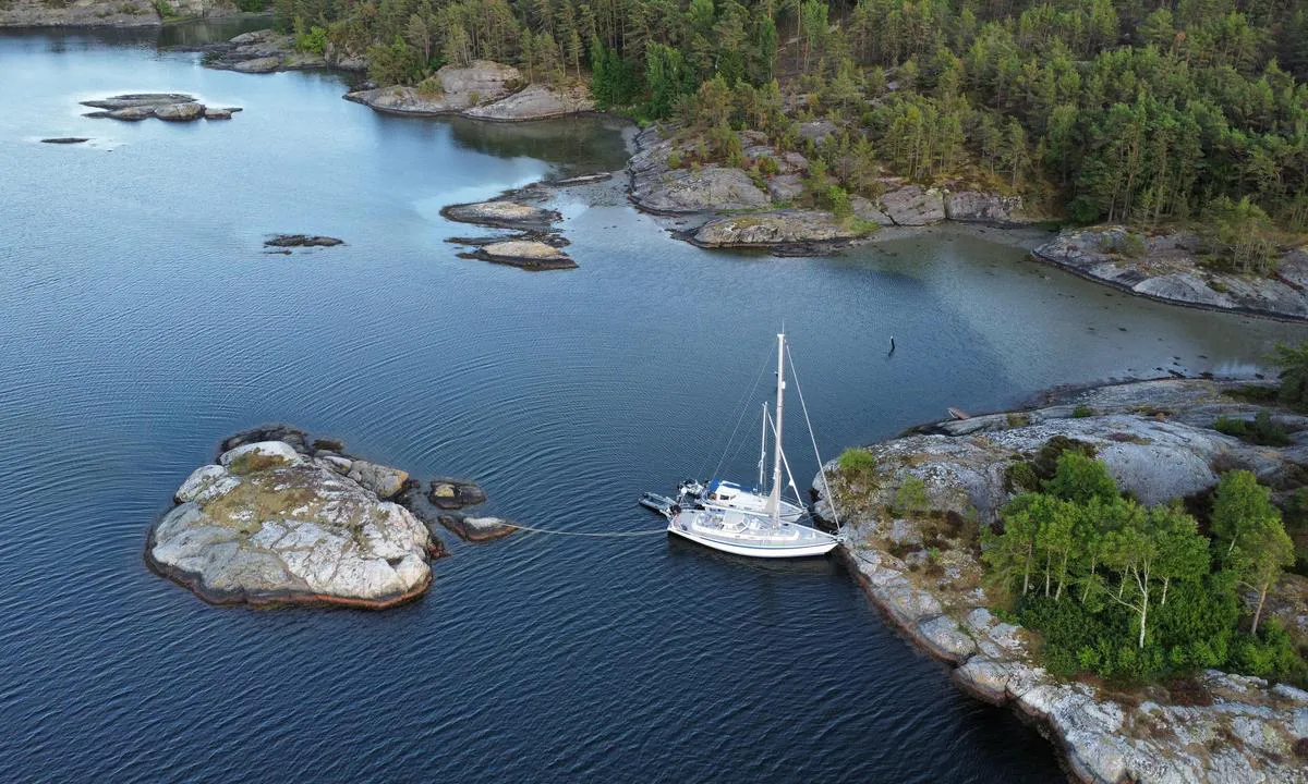 Lövö - SXK Västkust bouy: Sailboats moored towards land with aft lines onto the small island behind the boats.