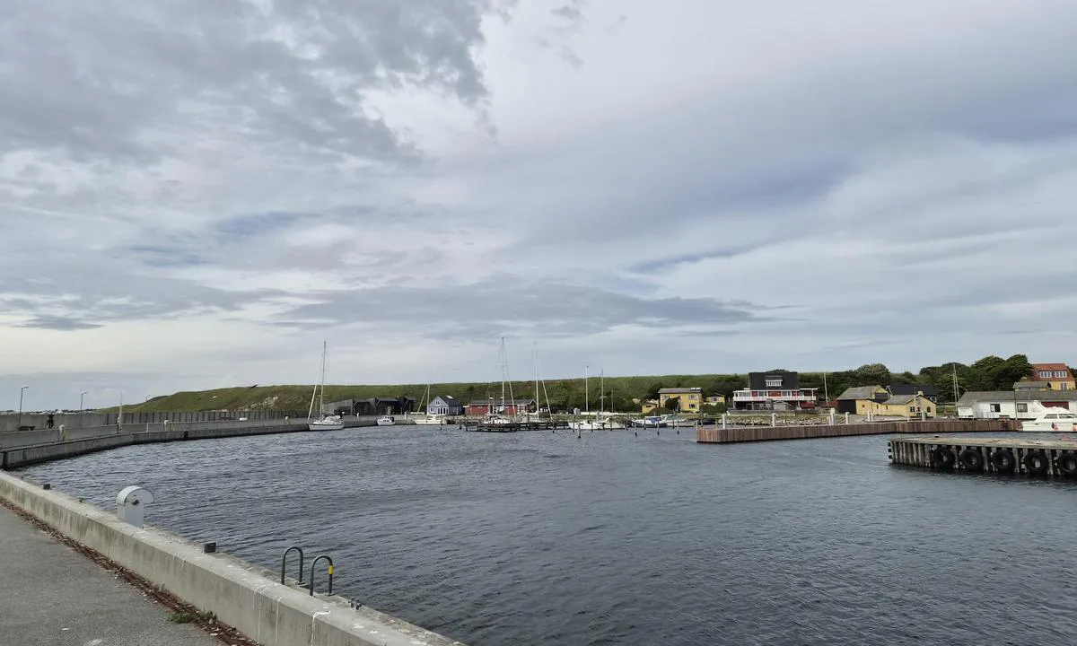Sejerø Havn: Havna sett fra SV. Lang kai på innsiden av molo. Fortøjning også mulig langsides til høyre etter drivstofftank. Fortøyning mellom påler innerst i havna.