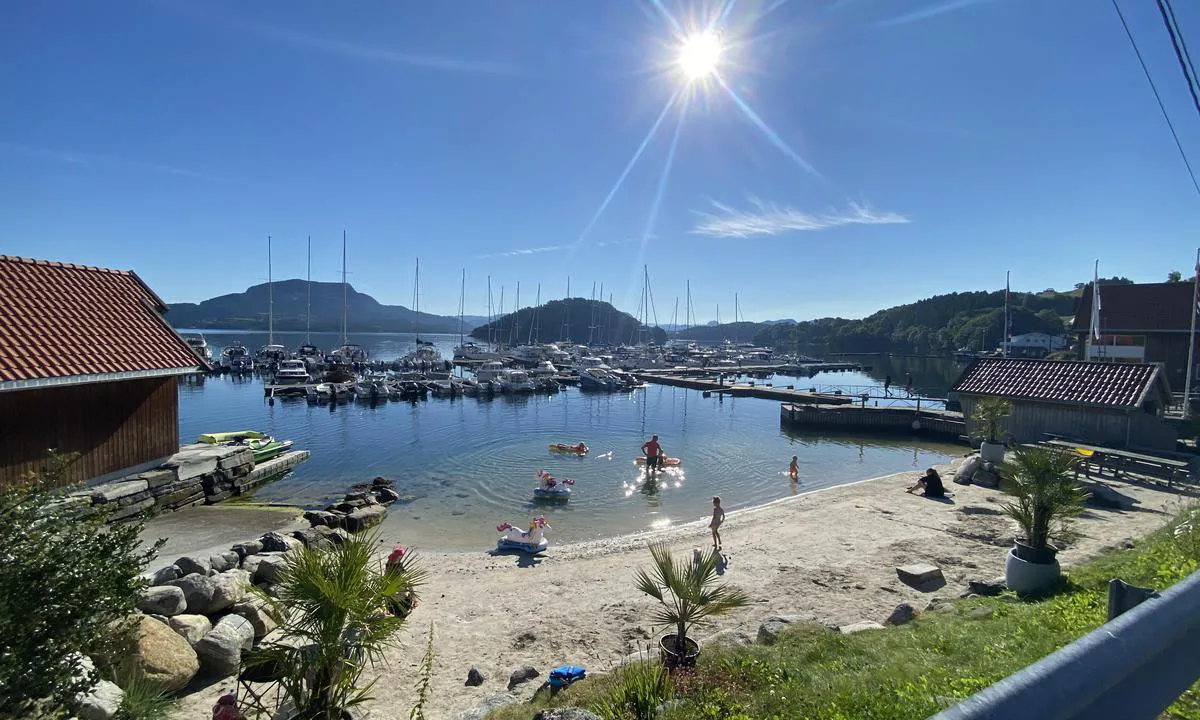 Skartveit Gjestehavn: Tidlig morgen med sol fra blå himmel.De ivrigste badegjestene er allerede på plass  Gjestehavna og Servicebygg i bakgrunnen